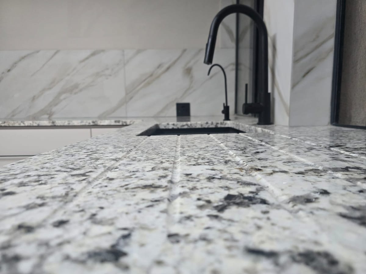 Close-up of the speckled granite countertop and black gooseneck tap