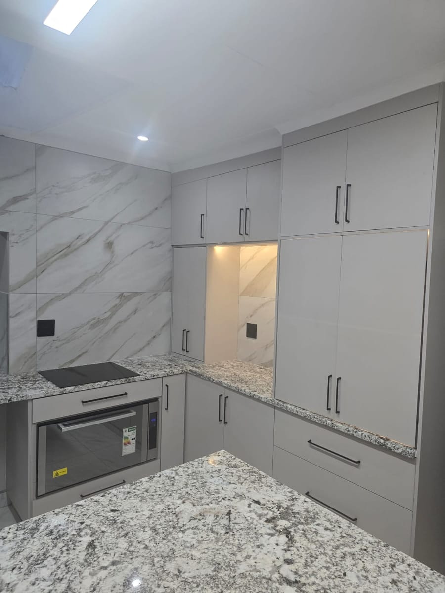 Built-in oven, marble-look wall tiles and floor-to-ceiling cabinets with lit appliance nook