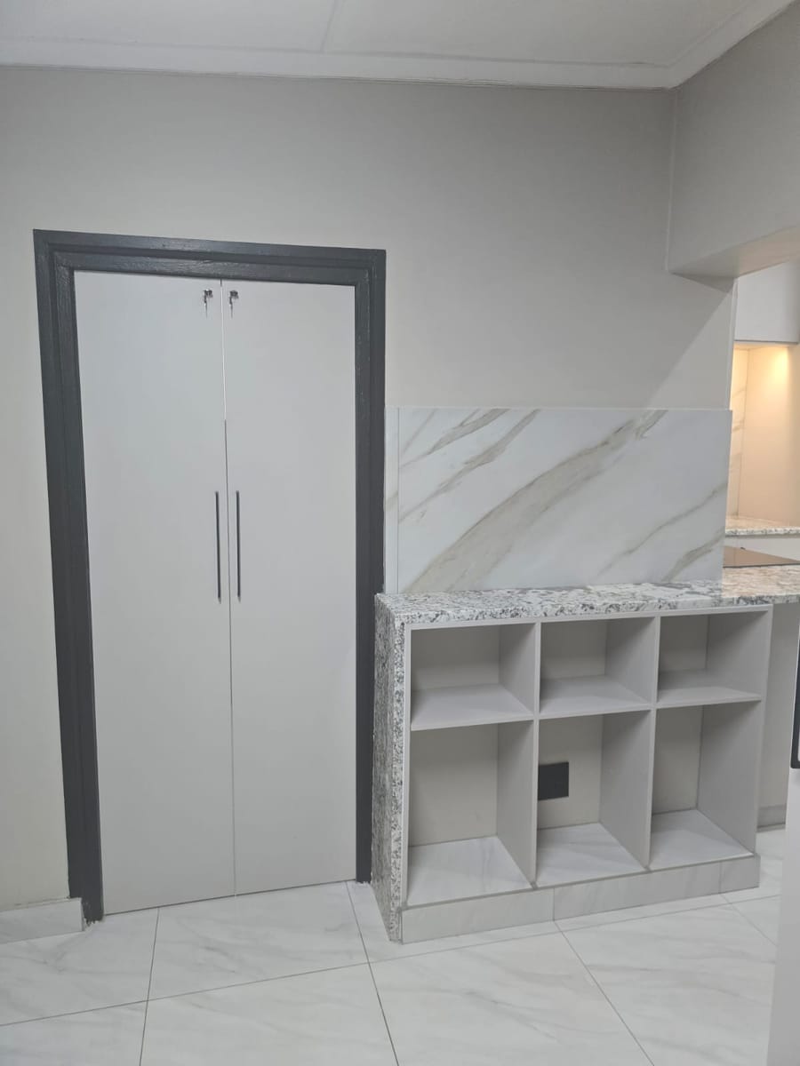 Pantry cupboard with dark frame next to open cube shelving under a granite top