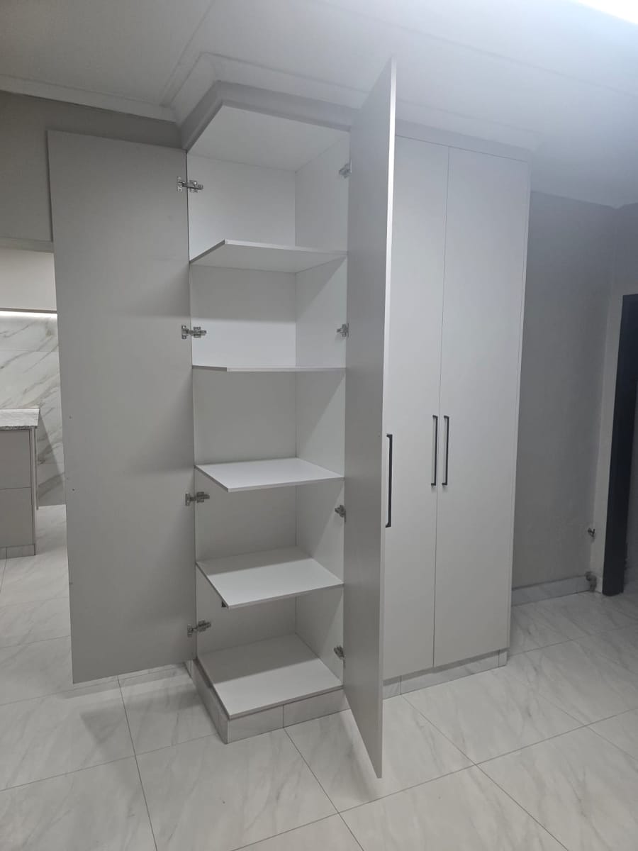 Open pantry unit with adjustable shelves beside tall cupboards