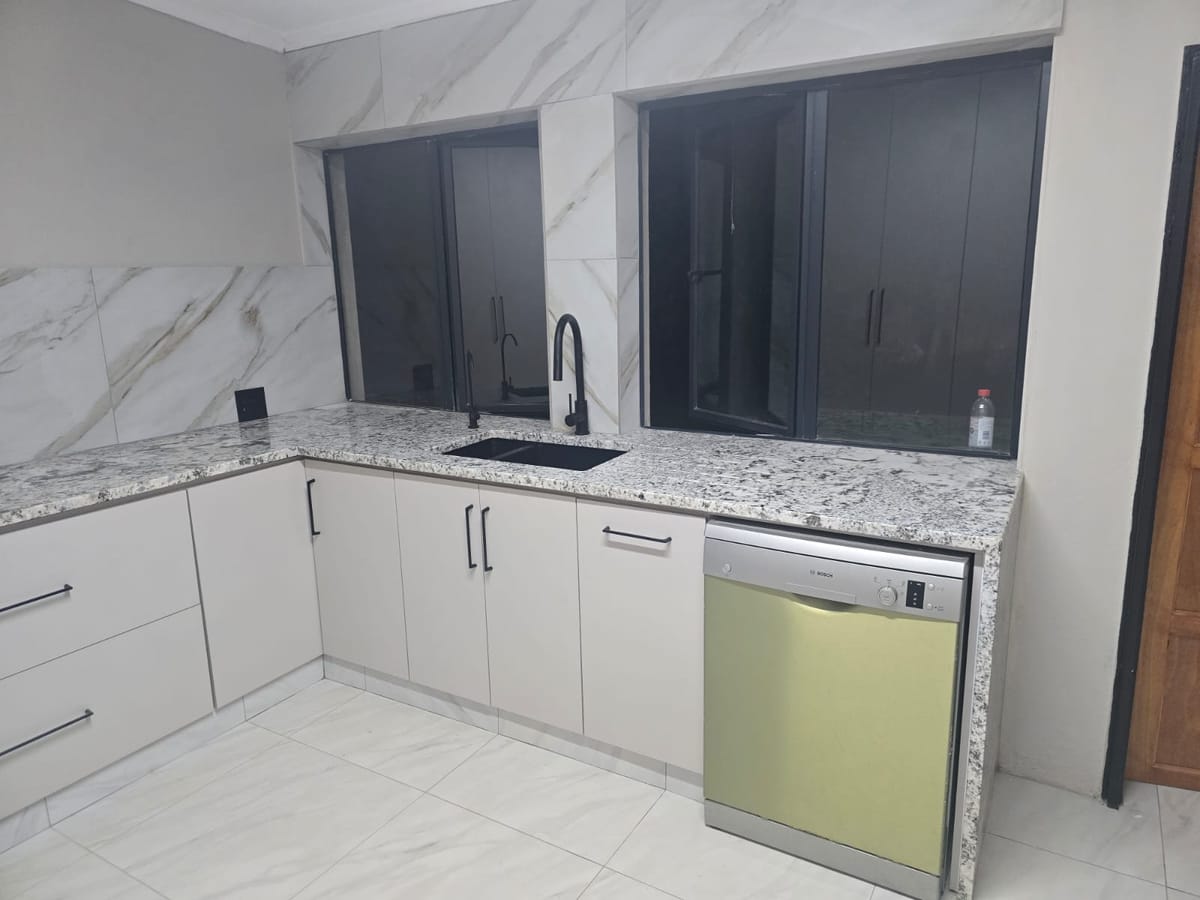 Kitchen renovation by MZ Steel & Construction with white cabinets and granite tops